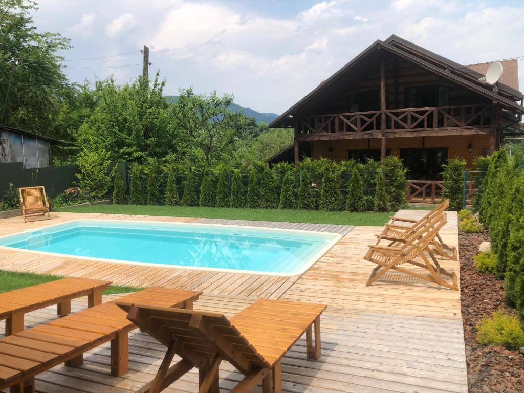 a swimming pool with benches and a house at Панська Господа in Vyzhnytsya