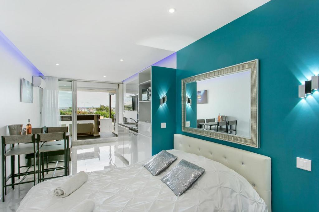 - une chambre avec des murs bleus et un lit avec un miroir dans l'établissement Village Naturiste R4N - Le Wallis Port Nature Coursive, au Cap d'Agde