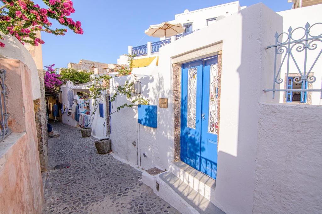 een smal steegje met blauwe deuren op witte gebouwen bij ArcadOIA House in Oia