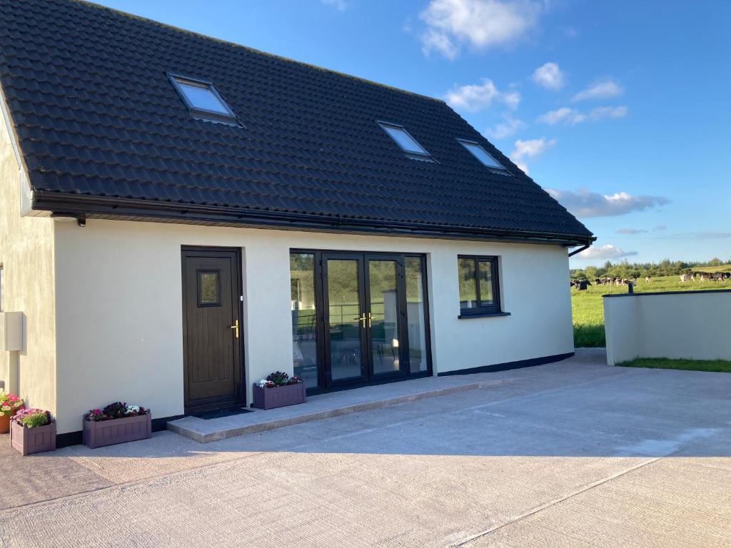 a white house with a black roof at The Grasslands Holiday Home, in Cork