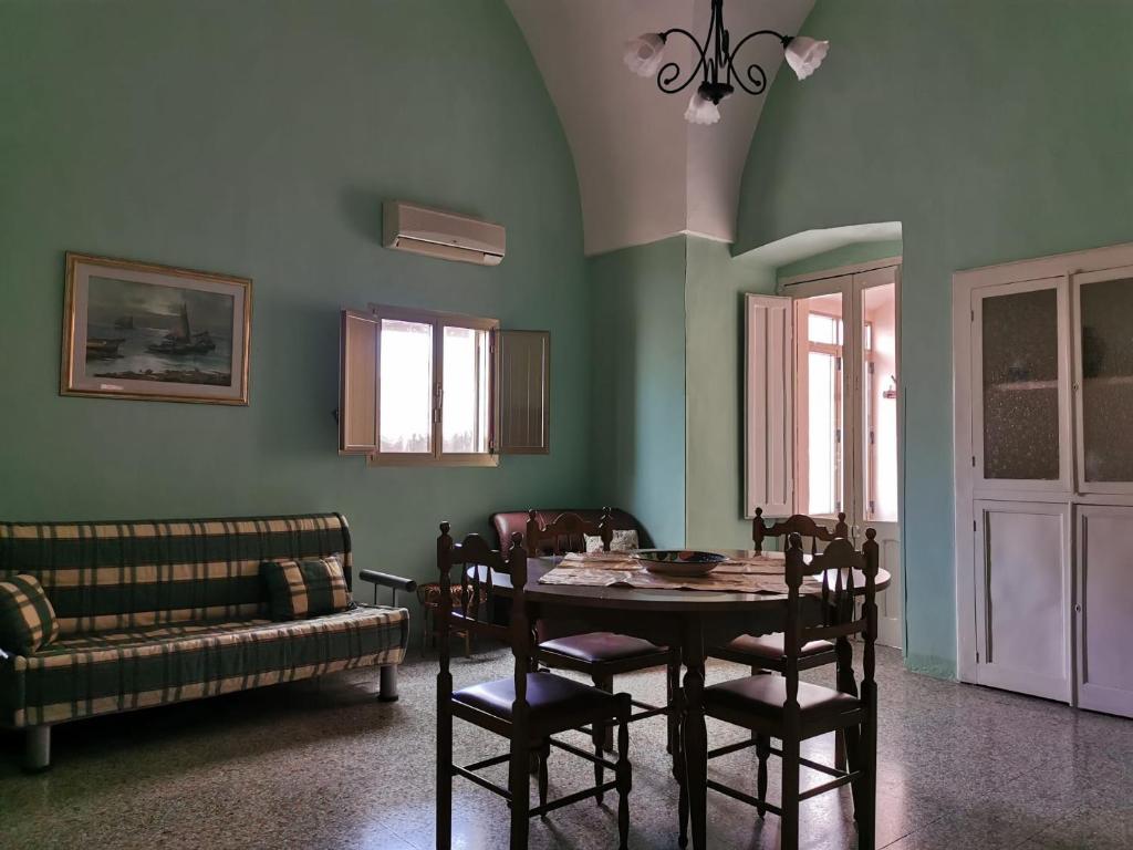 una sala da pranzo con tavolo, sedie e divano di Casetta Stellata Monteforte a Casarano
