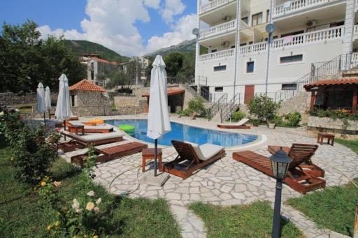 a swimming pool with chairs and umbrellas next to a building at Apartments Oasis in Budva
