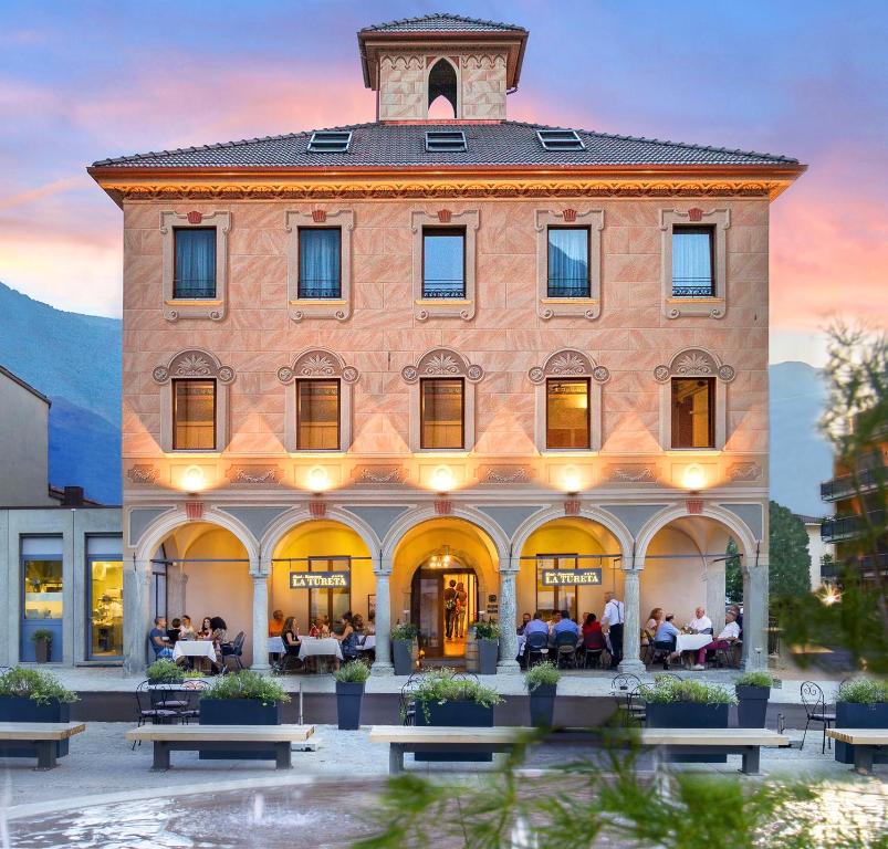 un gran edificio con gente sentada en mesas delante de él en Boutique & Business Hotel La Tureta, en Bellinzona