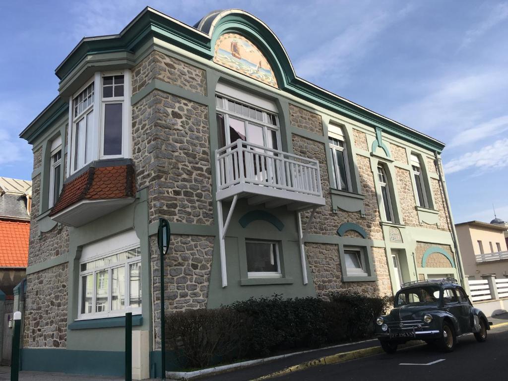 une vieille voiture garée devant un immeuble dans l'établissement Sans Adieu, à Wimereux