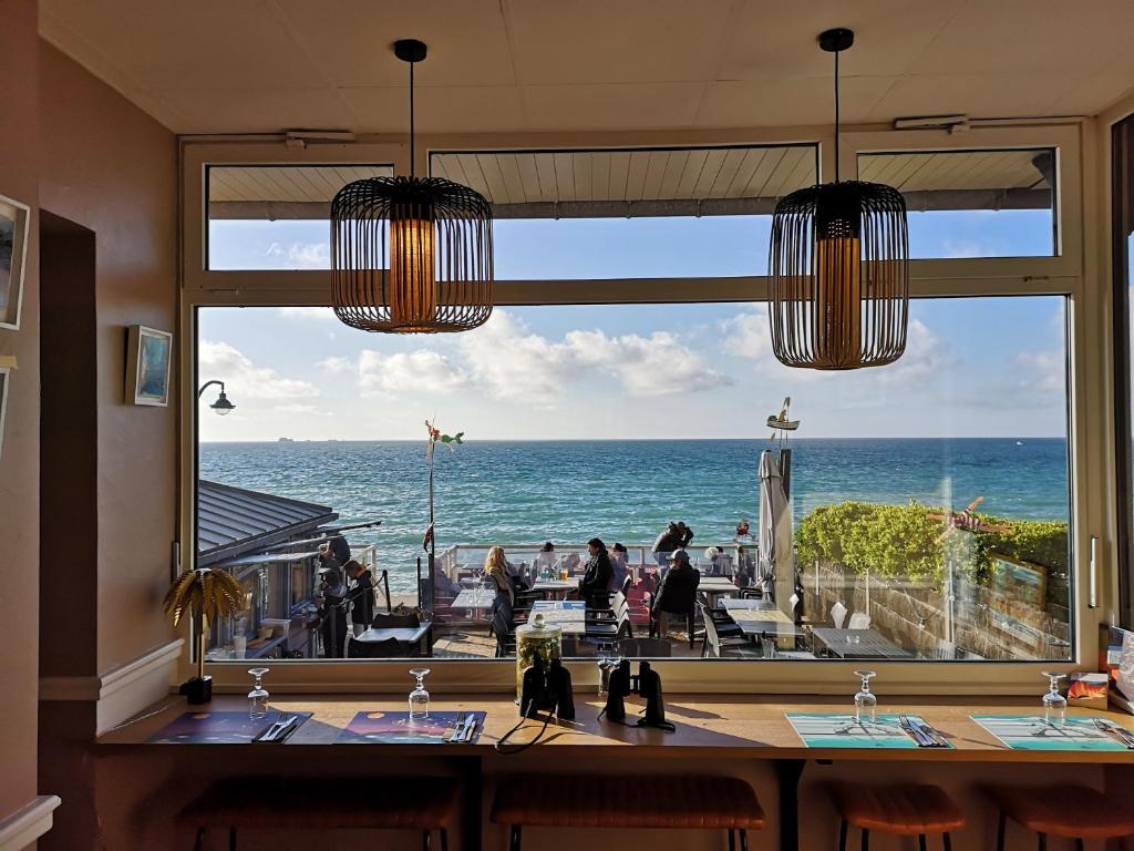 een restaurant met uitzicht op de oceaan vanuit een raam bij Les Charmettes in Saint-Malo