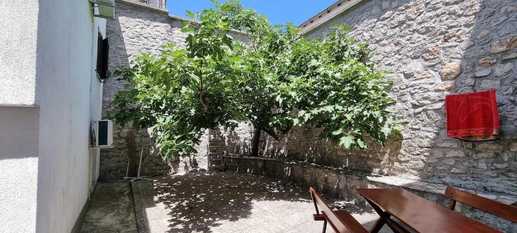 a tree sitting next to a stone building with chairs at Holiday home Marija in Karlobag