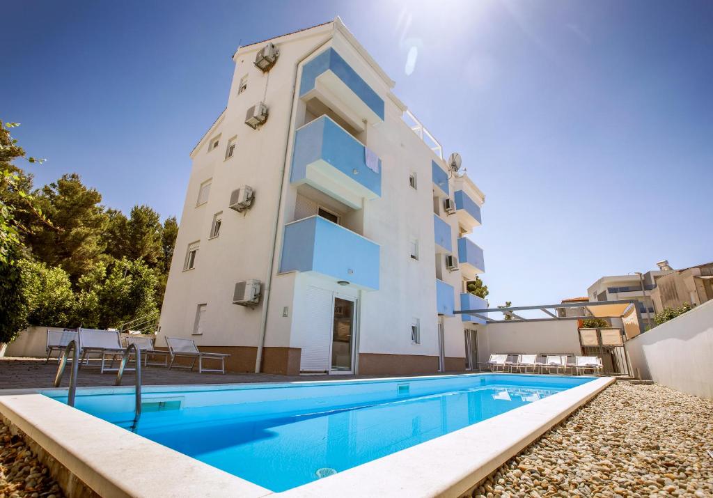 an apartment with a swimming pool in front of a building at Villa Stipe in Podstrana