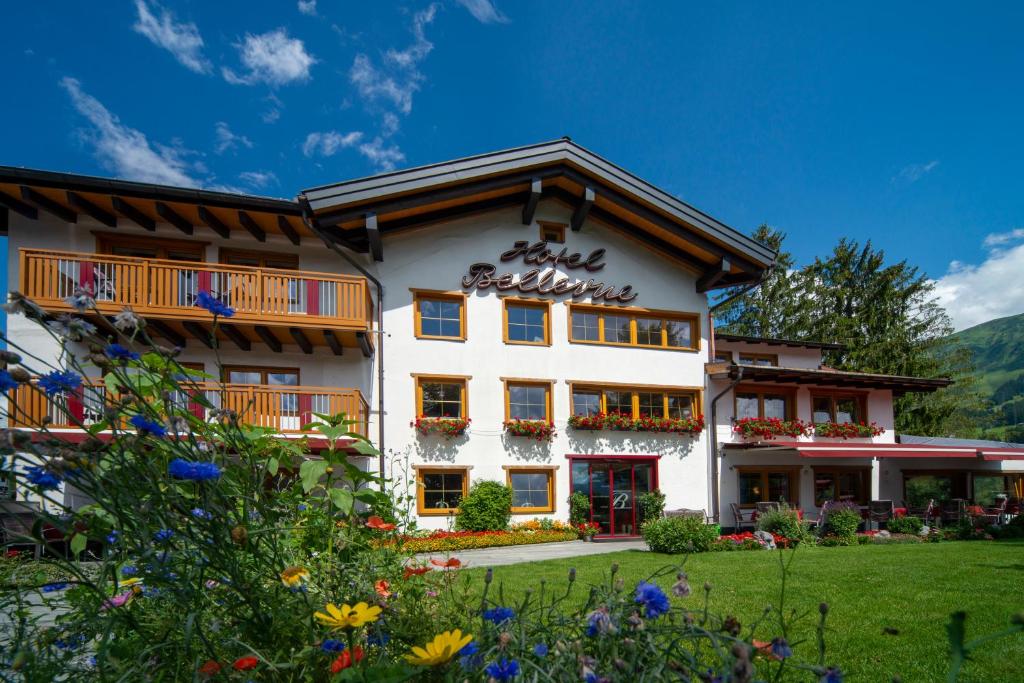 a large white building with flowers in front of it at Hotel Bellevue in Riezlern