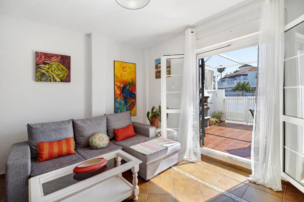 een woonkamer met een grijze bank en een glazen schuifdeur bij Casa Costa Ballena Dahlia in Costa Ballena