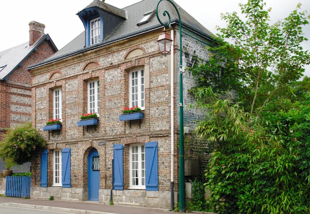 um antigo edifício de tijolos com portas e janelas azuis em Villa Valentine em Veules-les-Roses