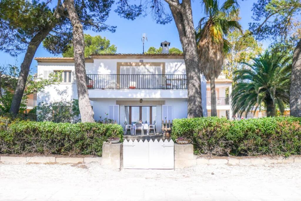 a white house with trees in front of it at Waterfront 3 Bedroom Beach Apartment in Alcudia