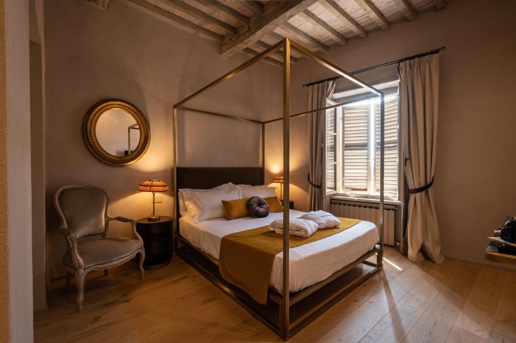 a bedroom with a canopy bed and a chair at Drogheria e Locanda Franci in Montalcino