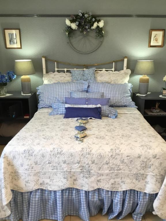 een bed met blauwe en witte lakens en kussens bij Aurelia Lodge - Apartment with Terrace in Souillac