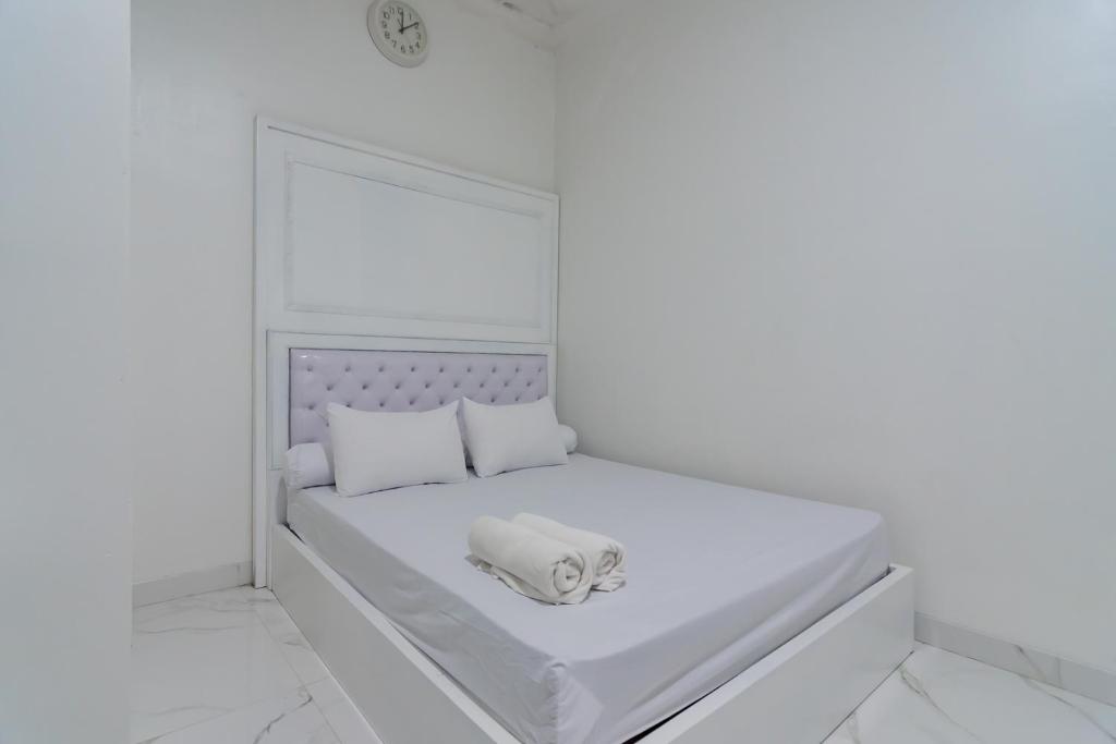 a white bedroom with a bed with a towel on it at Family Homestay Syariah Cirebon Mitra RedDoorz in Cirebon