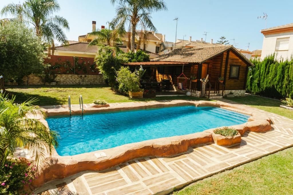 a swimming pool in a yard with a house at Casa de madera con piscina privada in Los Alcázares