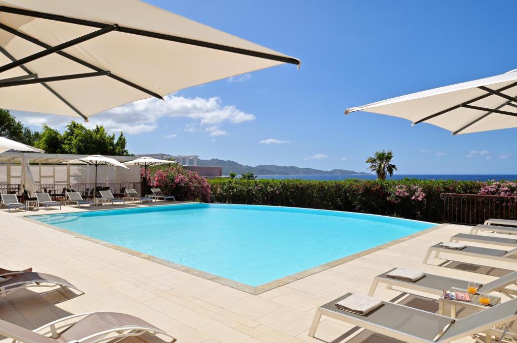 una piscina con sedie e ombrelloni di Hôtel Demeure Loredana a Saint-Florent