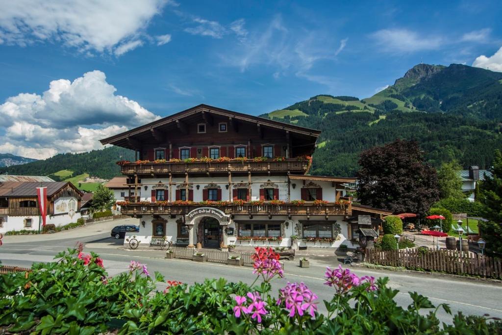 a building on the side of a street with mountains at Kaiserhotel Neuwirt in Oberndorf in Tirol