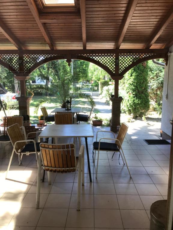 a patio with tables and chairs under a wooden pergola at Platanus Vendégház Zamárdi in Zamárdi