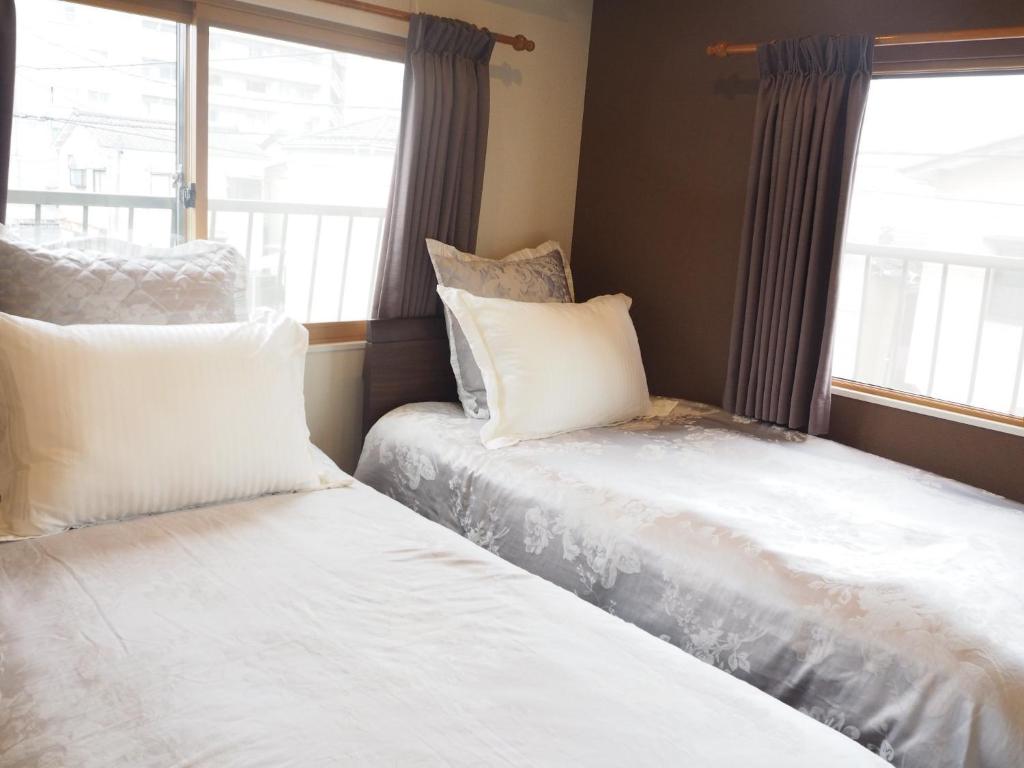 two beds in a room with a window at Harbour Inn & Suites - Vacation STAY 8829 in Niigata
