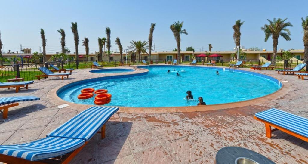 una gran piscina con sillas azules y palmeras en لافونتين البحيرة, en Al Khobar