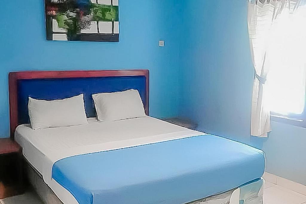 ein blaues Schlafzimmer mit einem Bett mit blauer Wand in der Unterkunft RedDoorz near Pantai Citepus Pelabuhan Ratu in Sukabumi