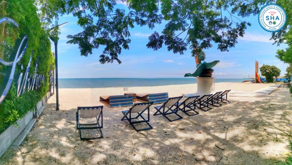 eine Gruppe Stühle und ein Tisch am Strand in der Unterkunft Beach Walk Boutique Resort in Bangsaen