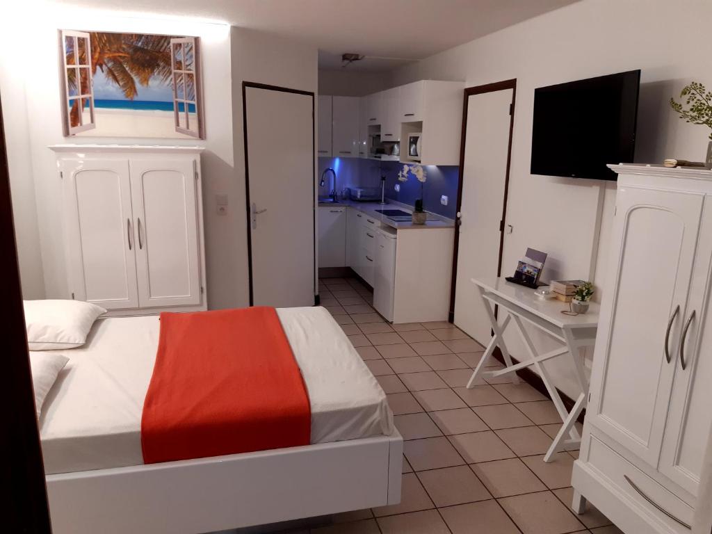 ein kleines Schlafzimmer mit einem Bett und einer Küche in der Unterkunft Studio Climatisé - Piscine-Plage - 1 à 2 personnes in Sainte-Anne