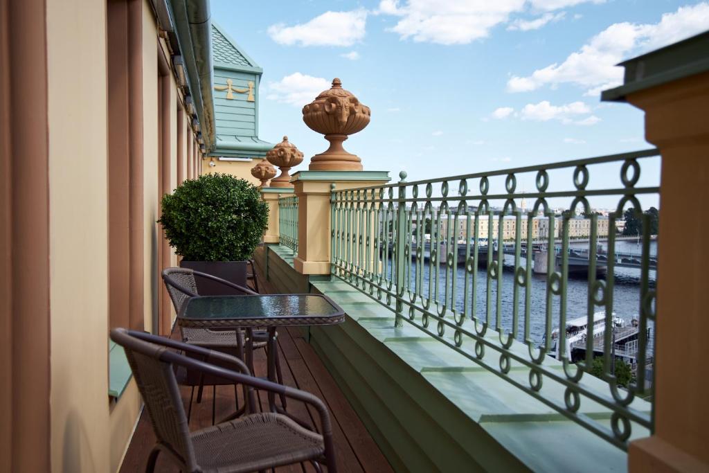 uma varanda com cadeiras e uma mesa e vista para a água em River Palace Hotel em São Petersburgo