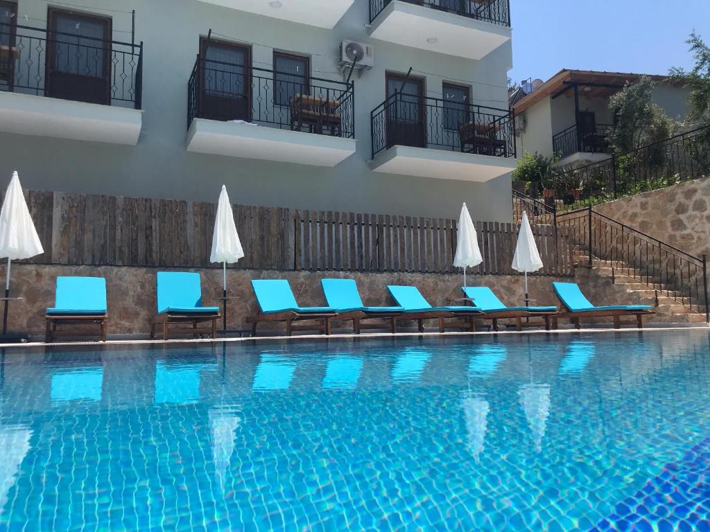 a swimming pool with chairs and umbrellas next to a building at St. Nicholas Pension in Patara