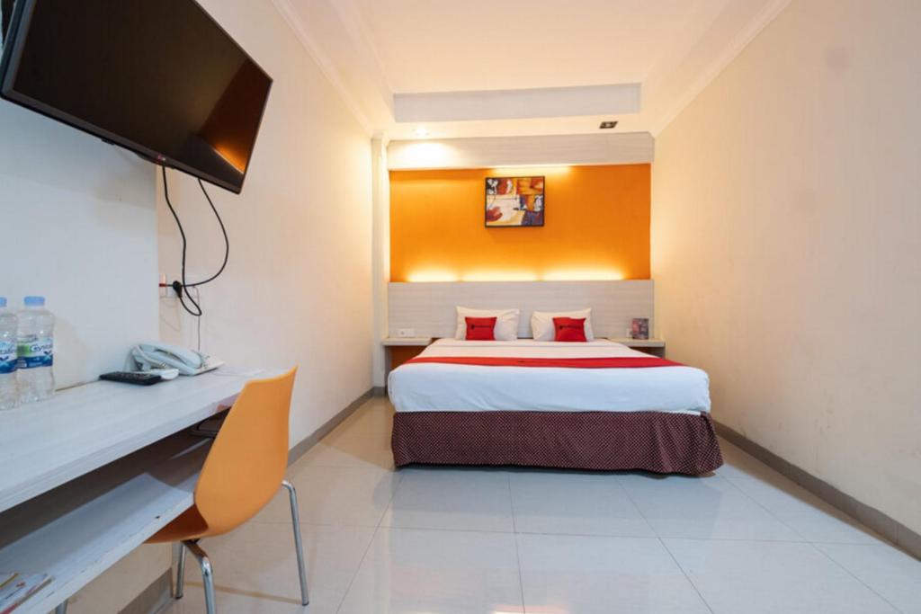 a hotel room with a bed and a desk at RedDoorz Plus @ Hotel Alden Makassar in Makassar