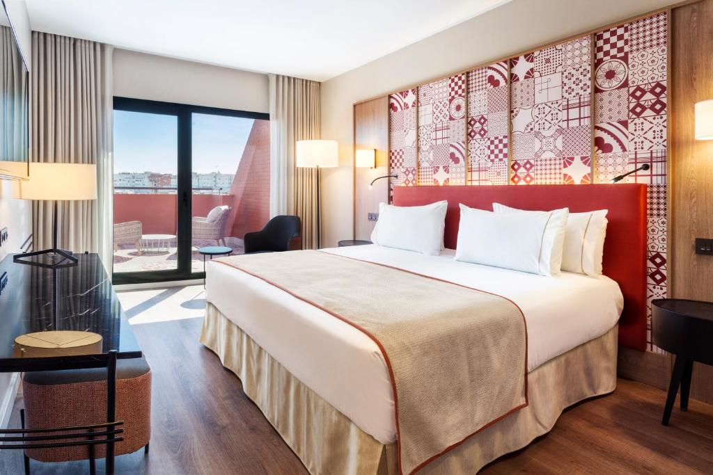 um quarto de hotel com uma cama e uma varanda em Eurostars Guadalquivir em Sevilha