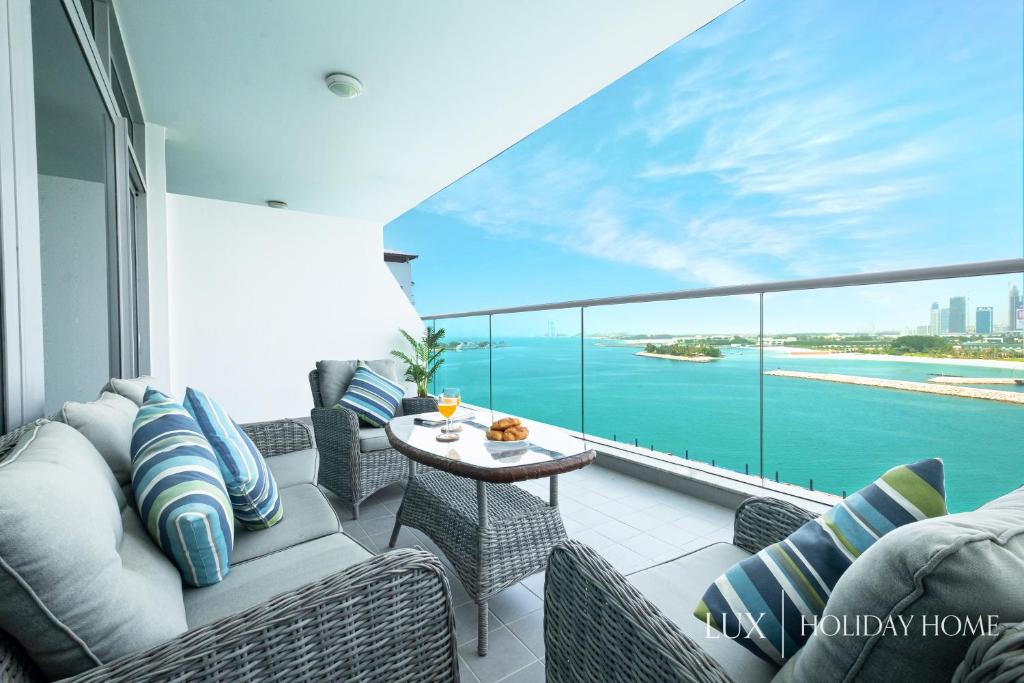 d'un balcon avec un canapé, des chaises et une table. dans l'établissement LUX Opulent Island Suite 6 Burj View, à Dubaï