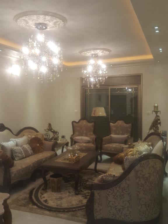 - un salon avec des lustres, des chaises et une table dans l'établissement Nablus luxury Residence, à Naplouse