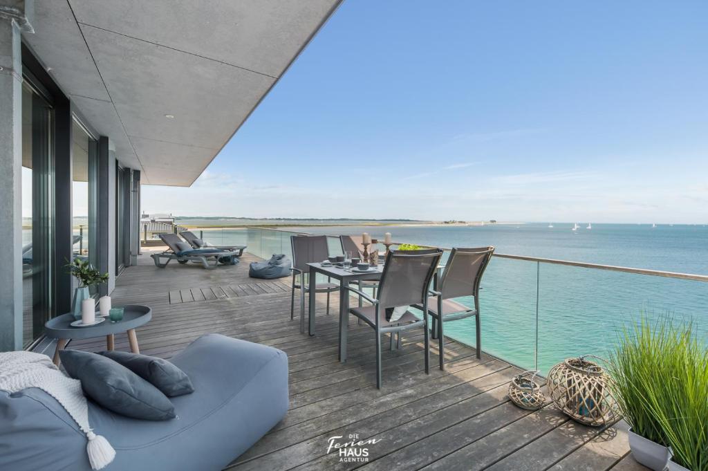 a balcony with a table and chairs and the ocean at Penthouse in Olpenitz