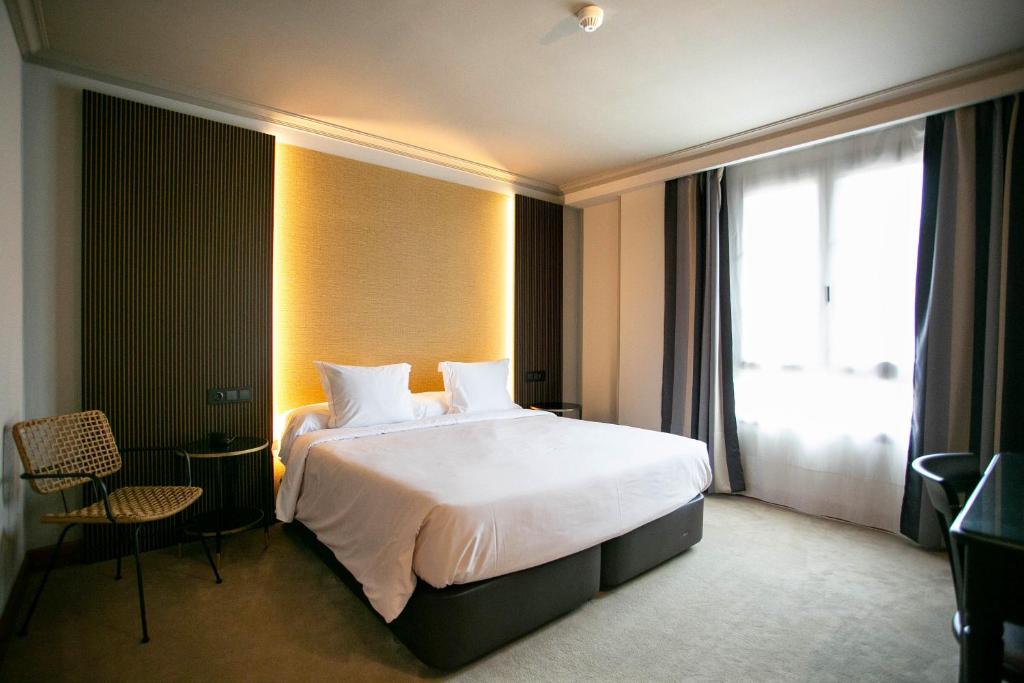 una camera d'albergo con un grande letto e una finestra di Hotel Sercotel Ciudad de Oviedo a Oviedo