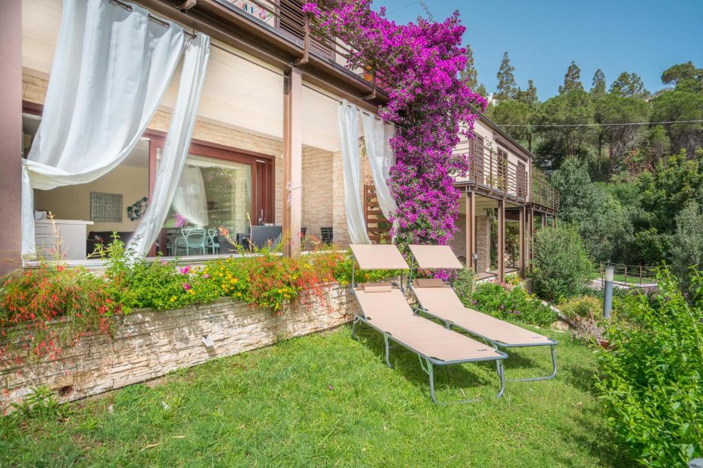 dos bancos sentados en el césped en un patio con flores en Villa Luna . Chia Eden Rock . Wifi AC, en Riva dei Pini