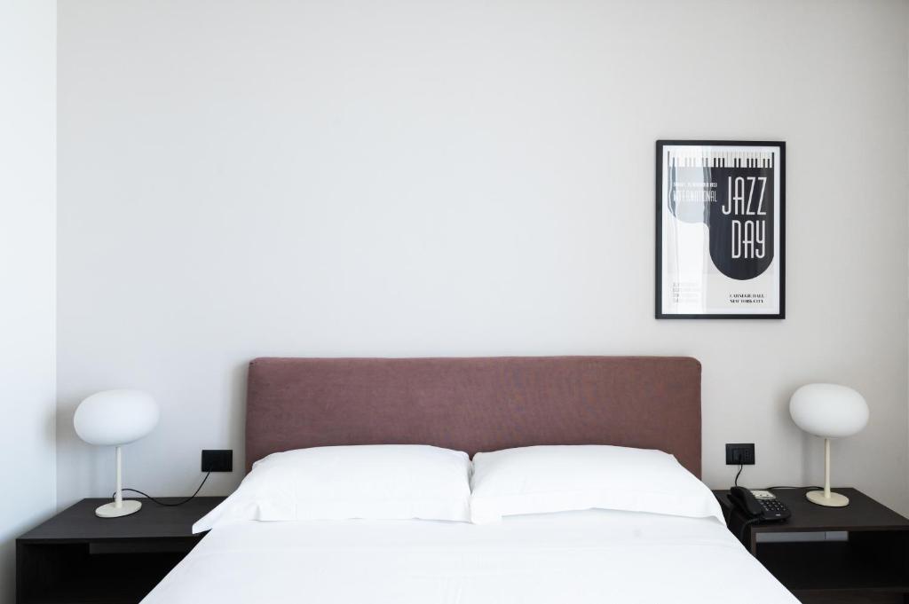 a bedroom with a bed with two lamps and a poster at Hotel Punta Tipa in Trapani