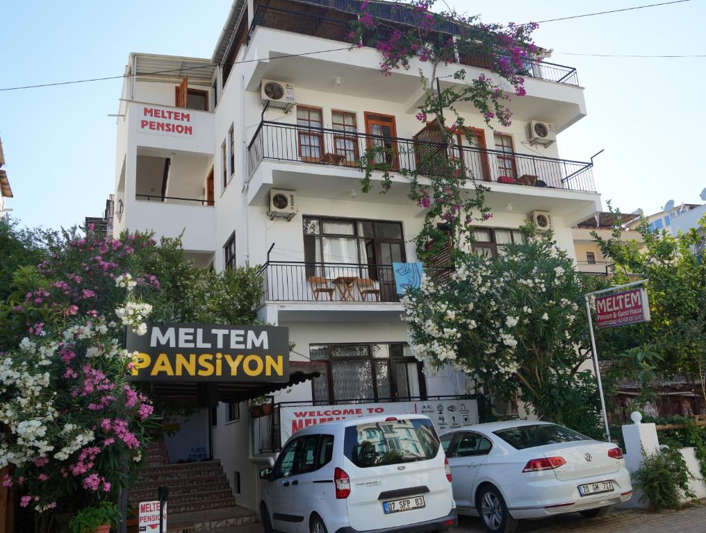 a white building with cars parked in front of it at meltem pansiyon in Kas