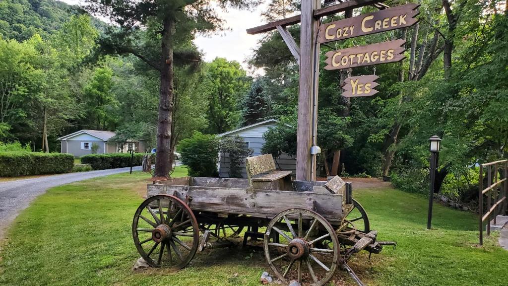 a wooden cart sitting in the grass next to a sign at Cozy Creek Cottages in Maggie Valley