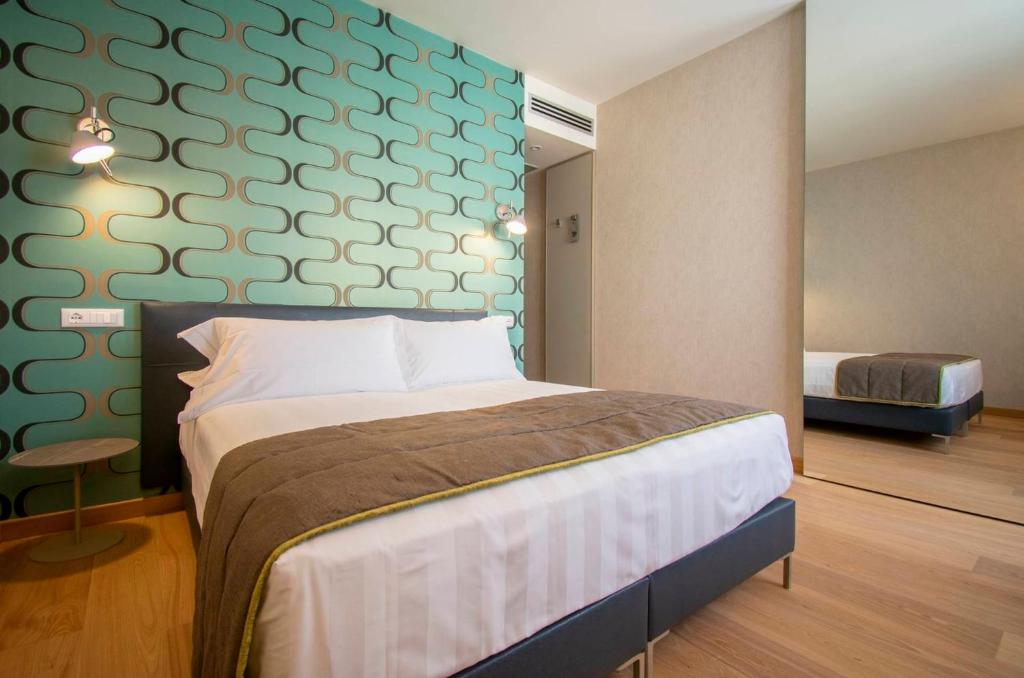een slaapkamer met een bed en een groene muur bij Hotel Medusa in Lido di Camaiore