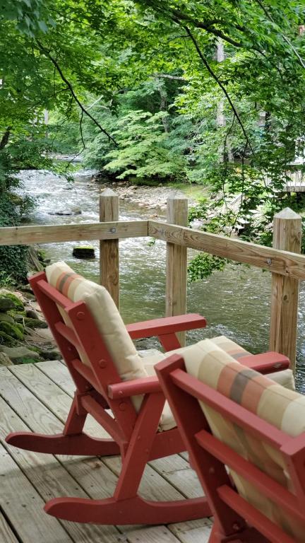 two chairs sitting on a deck near the water at Cozy Creek Cottages in Maggie Valley