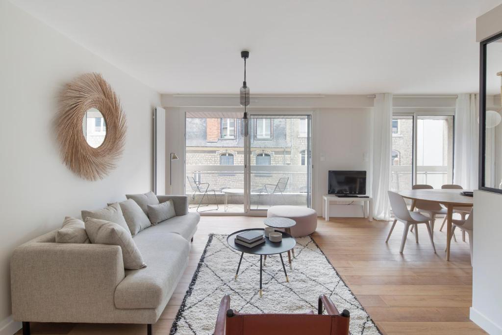 uma sala de estar com um sofá e uma mesa em L'Eden - Appartement familial au pied du Thabor em Rennes