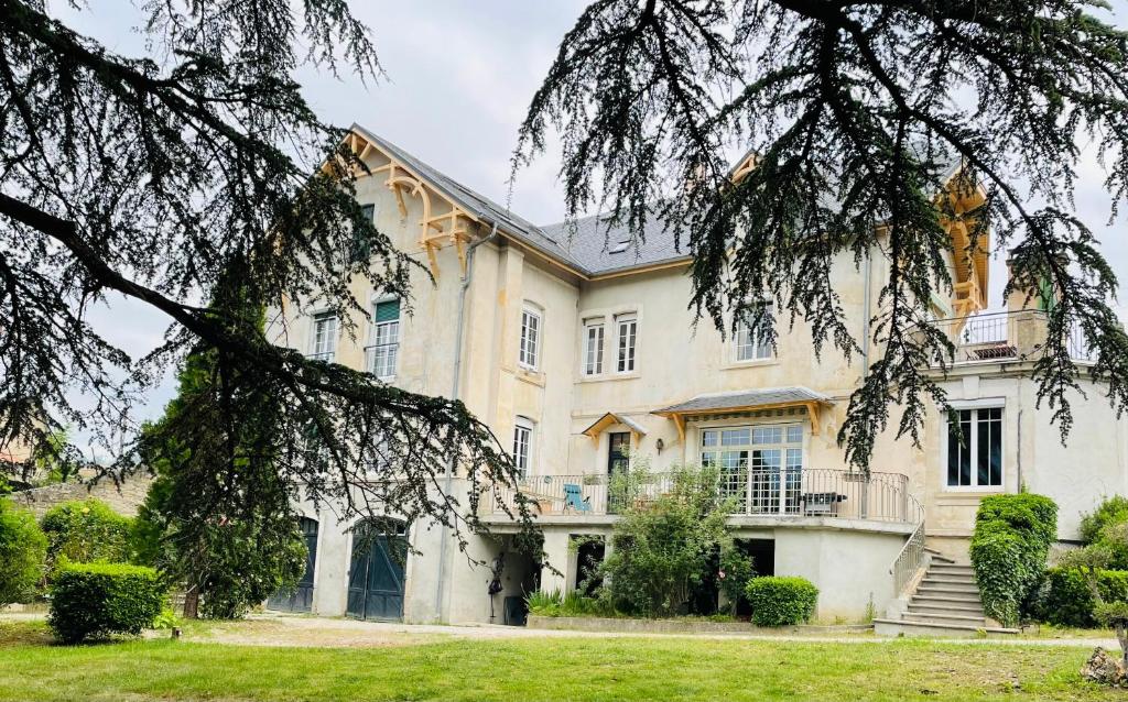 une grande maison blanche avec un arbre dans l'établissement Domaine des Ondes, à Millau