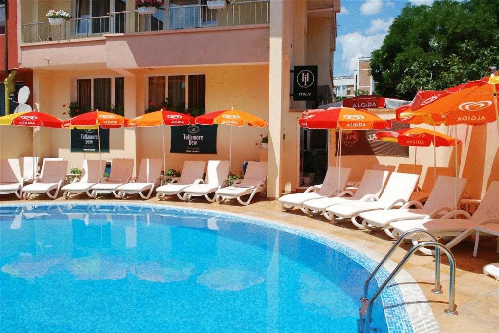 una piscina con sillas y sombrillas junto a un hotel en Italia Hotel, en Nesebar