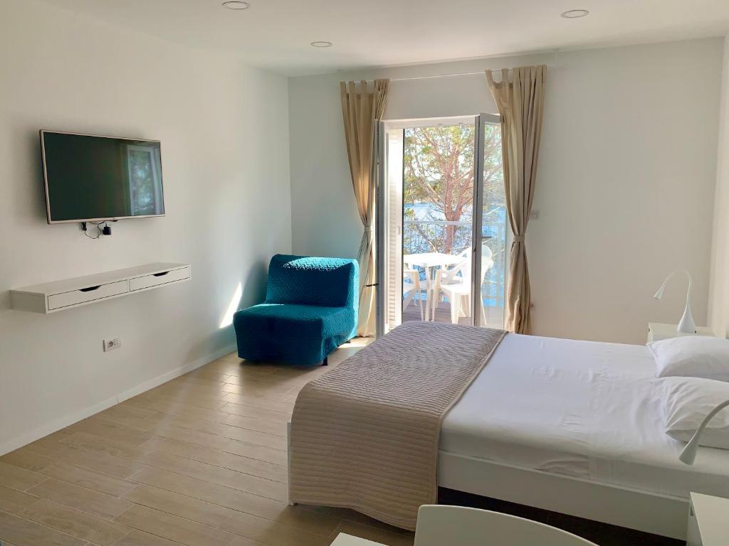 a bedroom with a bed and a blue chair and a television at Apartments Kaldana in Rab