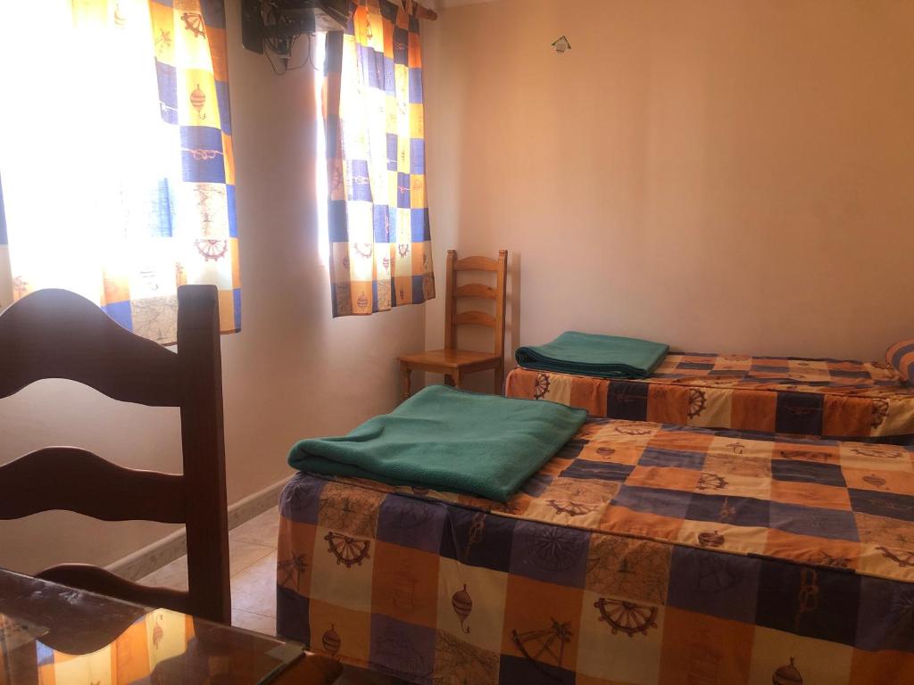 a room with two beds and a chair in it at HOSTAL ALGECIRAs in Algeciras