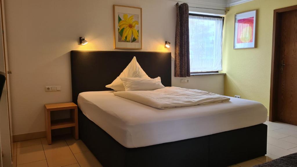 ein Schlafzimmer mit einem großen Bett mit weißer Bettwäsche in der Unterkunft Business Pension Gasper in Raunheim