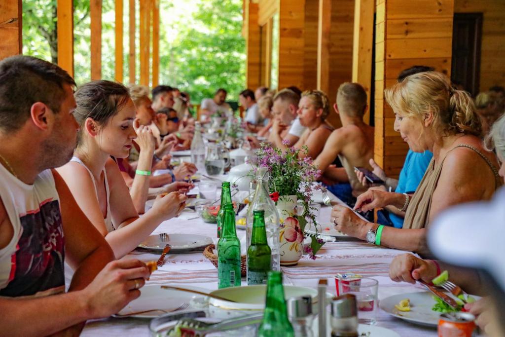 a group of people sitting at a long table at Bee Eco Guest House in Mollʼ e Shoshit