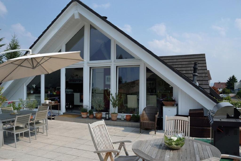 ein Haus mit einer Terrasse mit Stühlen und einem Sonnenschirm in der Unterkunft Zweit-Traumwohnung in Marburg an der Lahn