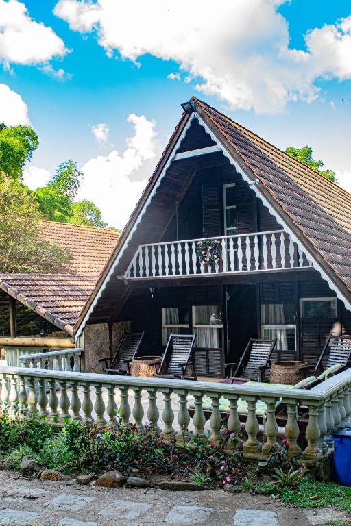 a house with a porch with chairs on it at Pousada Águas da Serra in Araras Petropolis